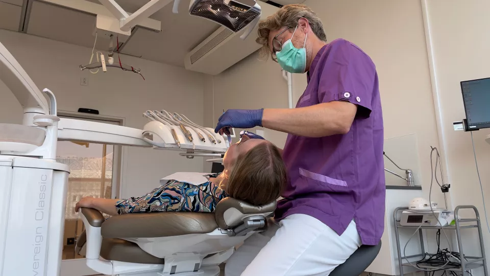 Photo of a dentist who examines the oral health of a woman.