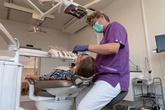 Photo of a dentist who examines the oral health of a woman.