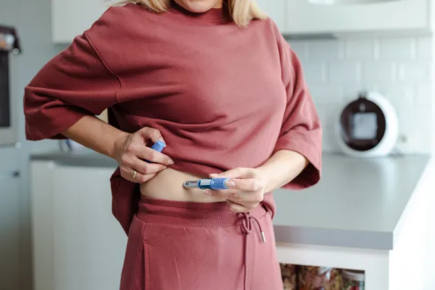 Photograph of a woman using an insulin pen.